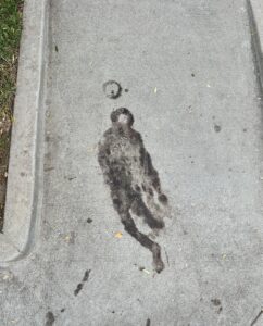 A random stain on a sidewalk that looks like a man, wearing a hat, floating up into space, the moon above his head.